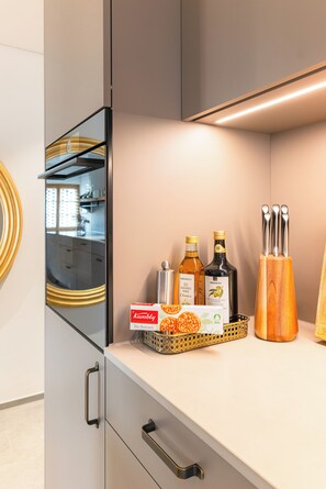 A kitchen counter with a box of Komby Bio pretzels, two bottles of olive oil, and a wooden knife block. - Peaceful Historic Hideaway – Golf, Lakes & Unspoiled Nature near Lucerne (Beromünster)