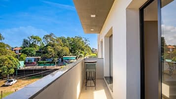 A balcony with a view of a residential area, a small table, and a chair.