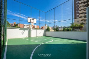 Eine überdachte Basketballhalle mit Netz, Korb und Spielfeld in Grün.