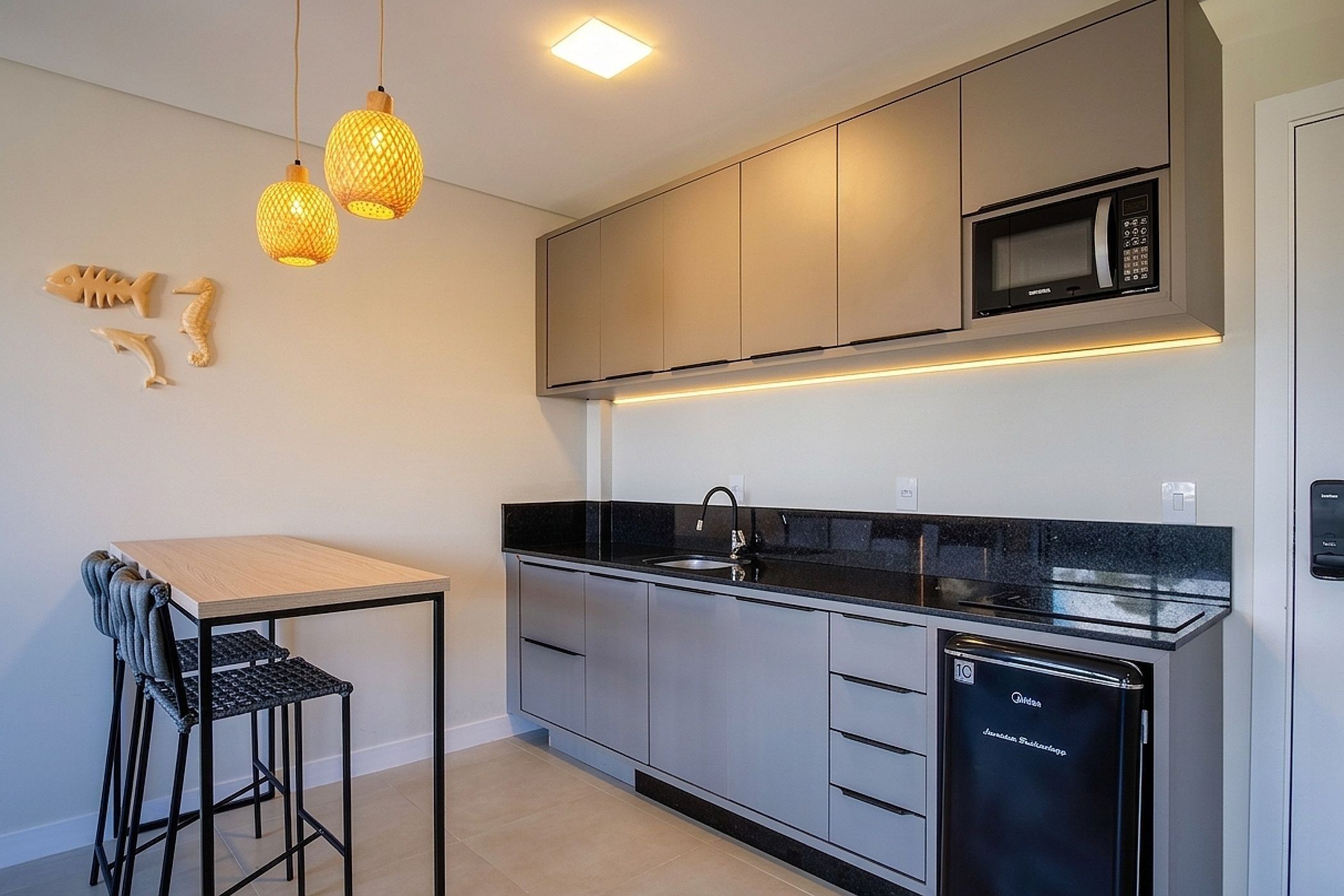 A modern kitchen with a dishwasher, a microwave, and pendant lights.