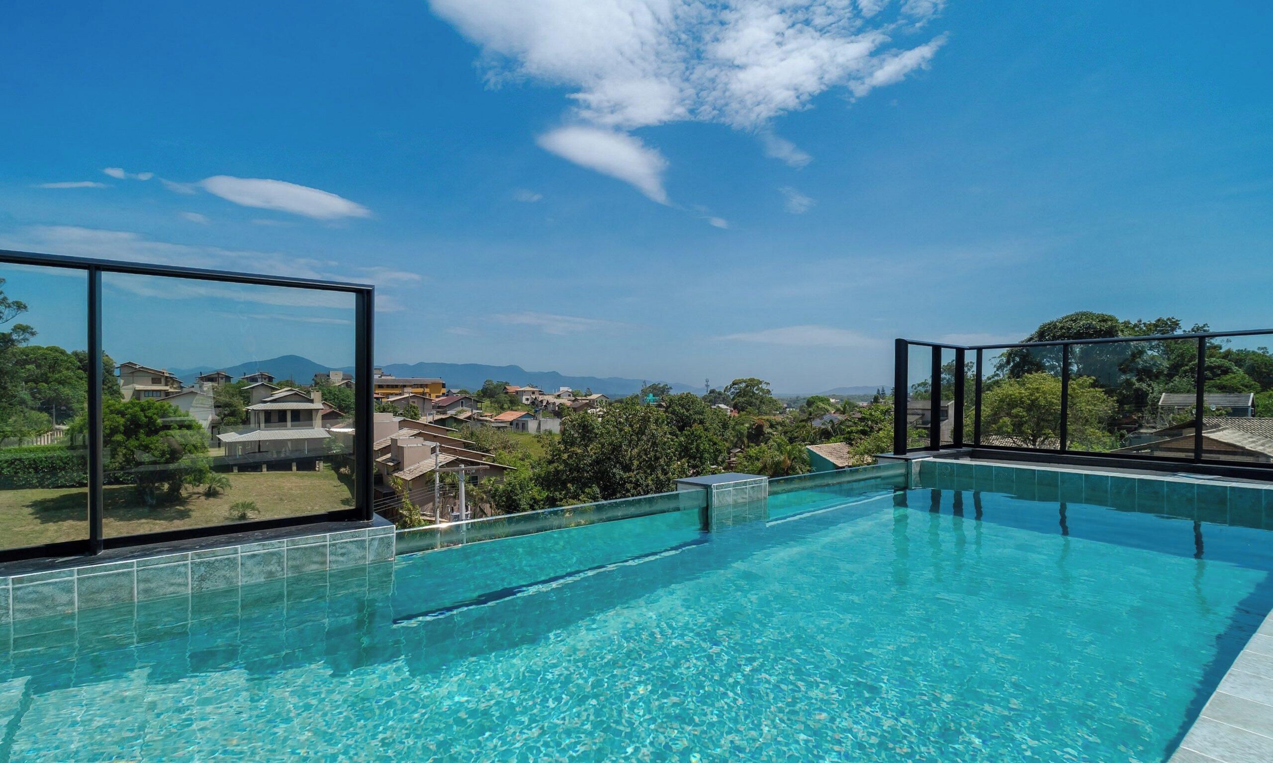 A clear blue swimming pool with a view of a residential area and mountains in the distance.