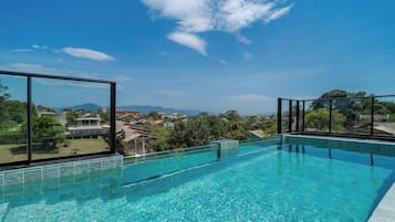A clear blue swimming pool with a view of a residential area and mountains in the distance.