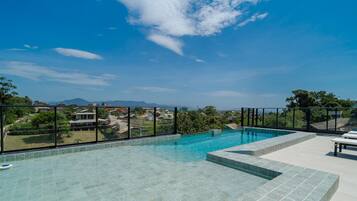 Una piscina infinita en la azotea con vistas despejadas del vecindario circundante y las montañas.