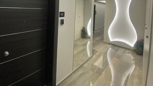 Un pasillo moderno con una puerta de madera oscura, un letrero con el número '01' y un piso reflectante.