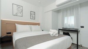 Una habitación de hotel moderna con una cama grande, un escritorio y dos obras de arte enmarcadas en la pared.