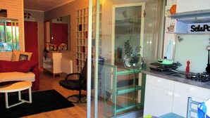 Una cocina moderna con separador de vidrio, un comedor con sofá rojo y un ventanal visible.