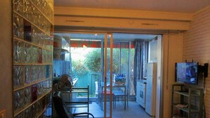 Habitación con puerta de cristal que da a un espacio exterior, un televisor en la pared y una silla.
