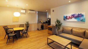 Un salon moderne avec un plancher en bois, une table à manger ronde entourée de chaises, un canapé, une table basse et un tableau accroché au mur.