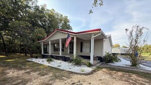 A single-story house with a porch, an American flag, and a mailbox.