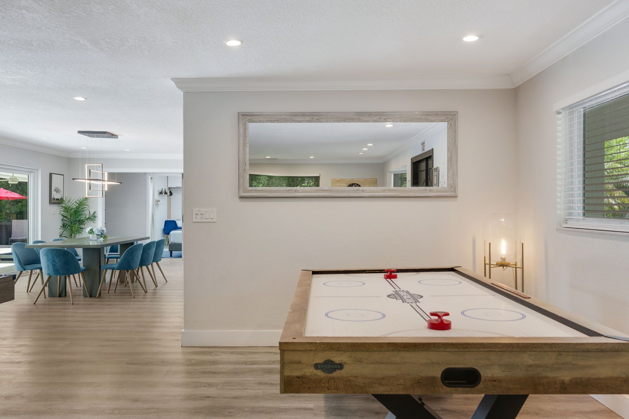 A modern interior with a pool table, dining area, and a mirror on the wall.