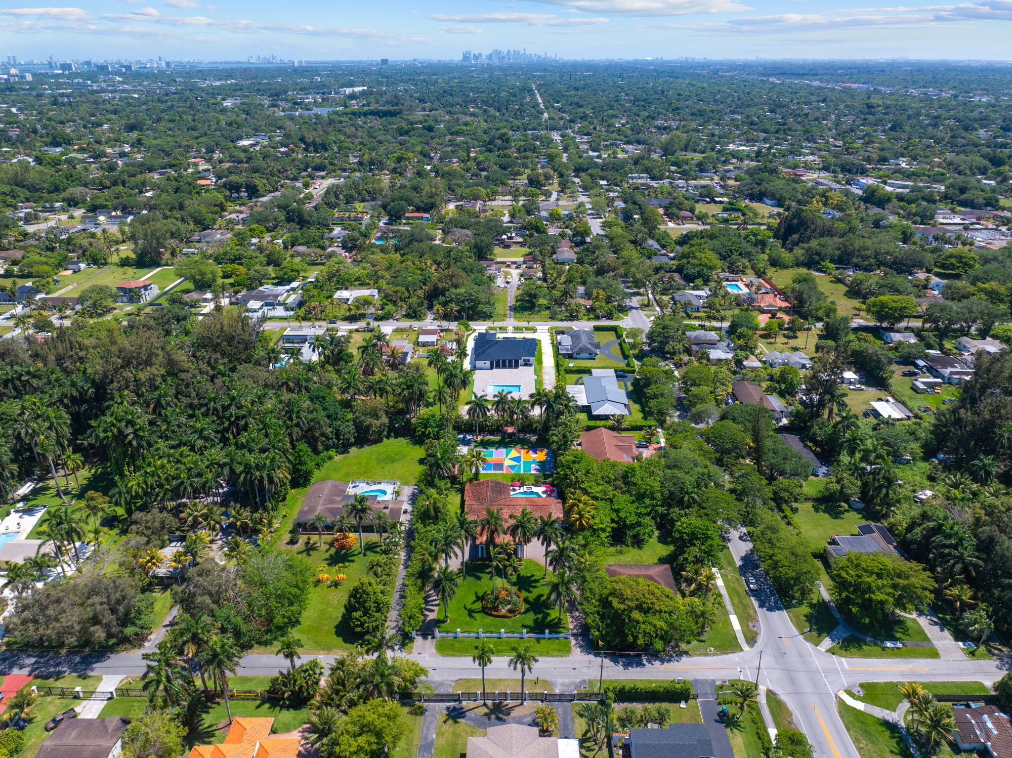 An aerial view of a residential area with houses, roads, and greenery.