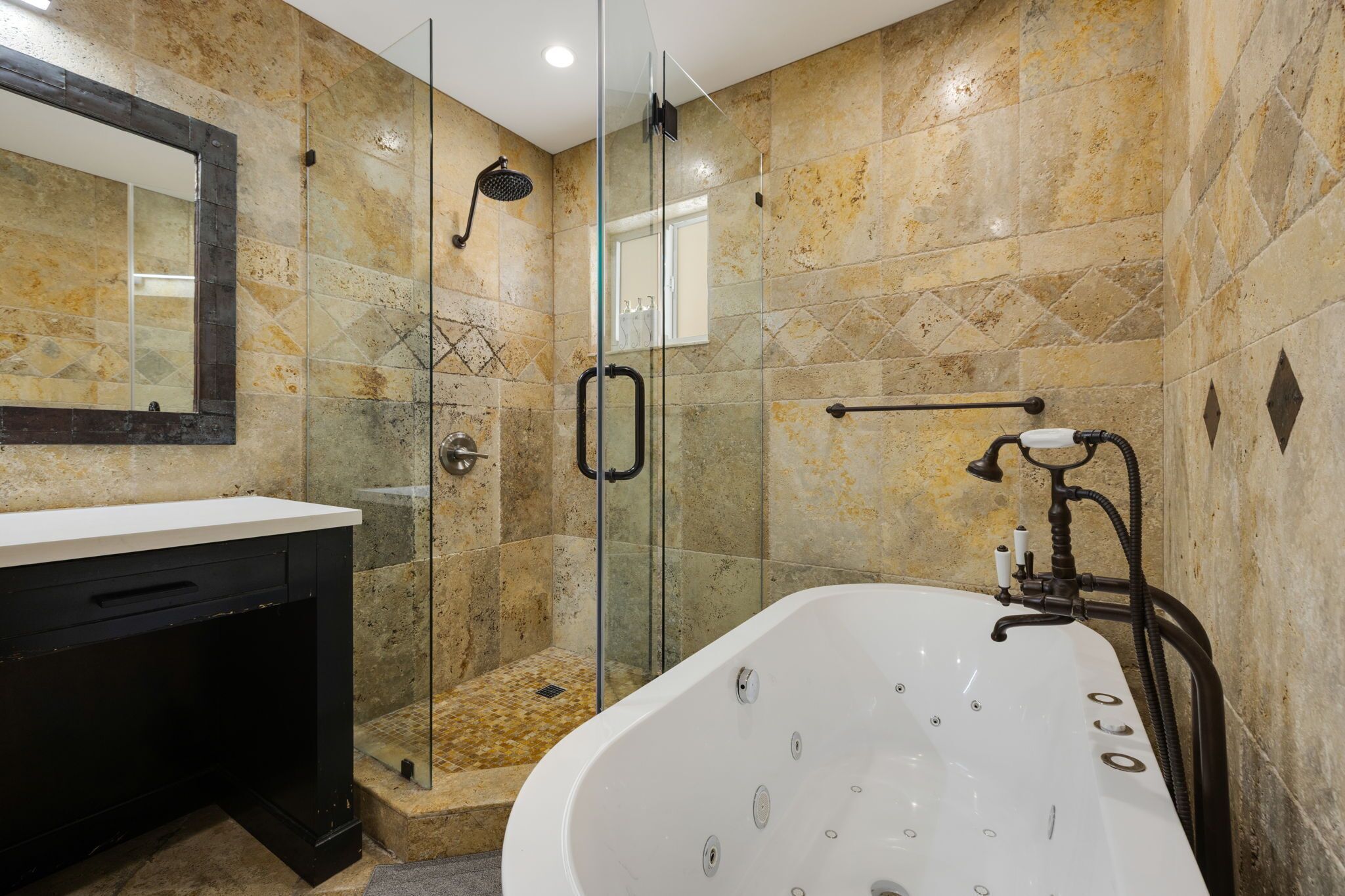 A modern bathroom with a glass-enclosed shower, a freestanding bathtub, and a vanity with a mirror.