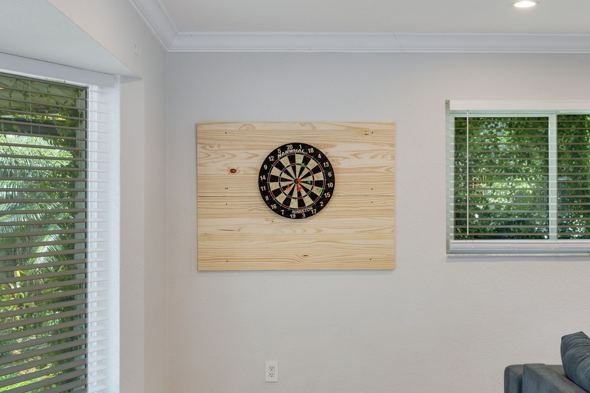 A dartboard mounted on a wall with a window to the right.