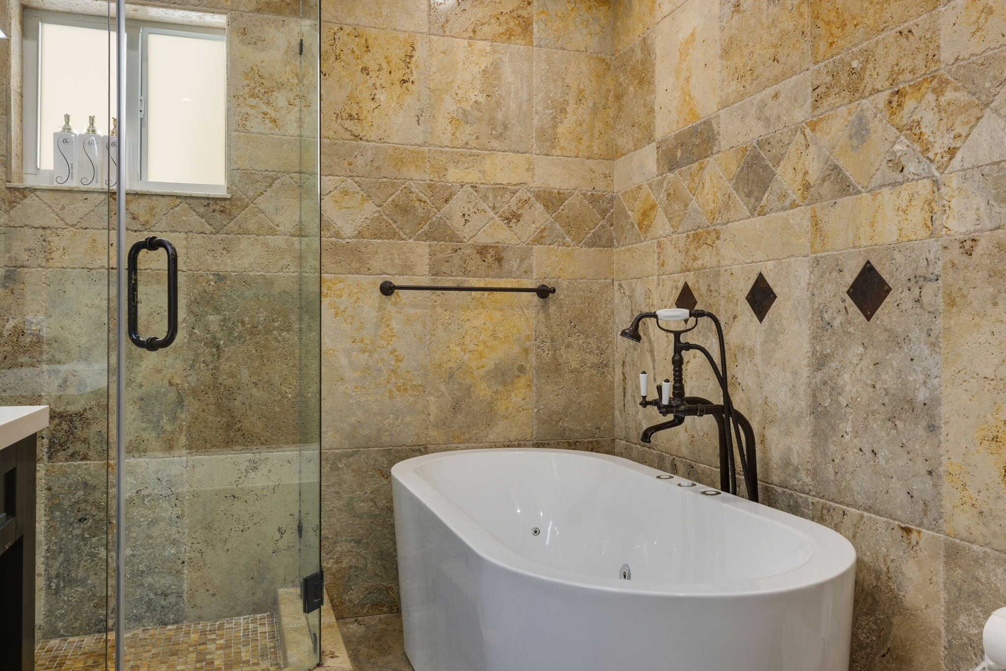 A bathroom with a bathtub, a glass shower enclosure, and a window.