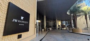A JW Marriott entrance with a modern design, glass doors, and a paved walkway. - Emaar Residences with Direct Access to Marina Mall. (Dubai)