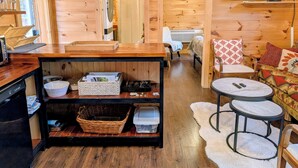 A wooden cabin interior with a kitchen area, a dining table, and a sofa. - Cozy Cabin Near Lake Burton Clayton - Dog Friendly! (Clarkesville)