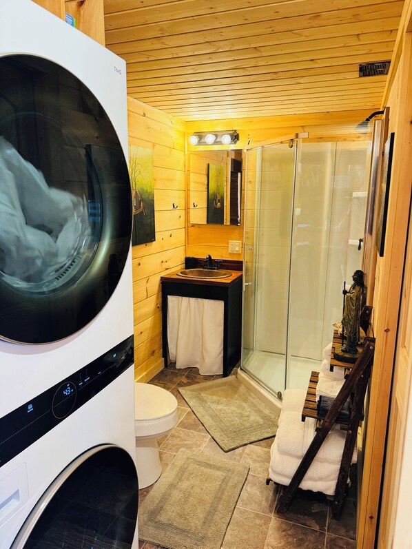 Een kleine badkamer met een wasmachine, toilet, wastafel en douchecabine.