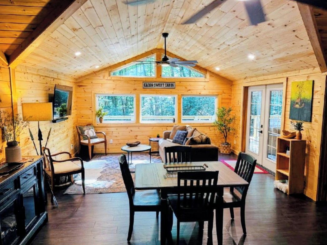 Ein Urlaushaus-Innenraum mit Essbereich, Sitzgelegenheiten und einem Fernseher.