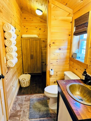 Een houten badkamer met toilet, wastafel en handdoekhouder.