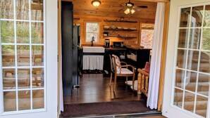 A wooden cabin interior with a kitchen, dining area, and a view of the forest. - Cozy Cabin Near Lake Burton Clayton - Dog Friendly! (Clarkesville)