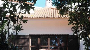 Un edificio con techo de tejas, paredes de piedra y cerca de madera.