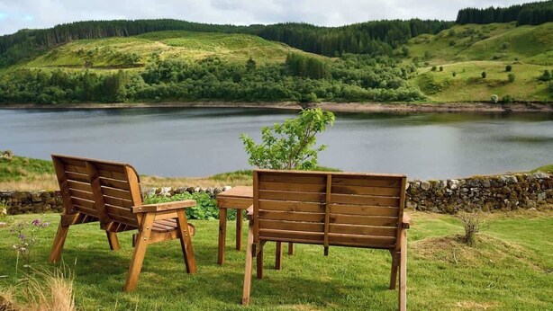 A lakeside view with a wooden bench and table, surrounded by greenery and hills. - Private Loch-side escape in the Scottish highlands (Oban)