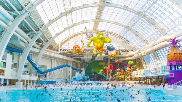 Un grande parco acquatico al coperto con diverse scivoli, una piscina centrale e varie attrazioni acquatiche.