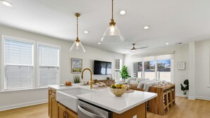 A modern kitchen with a central island, wooden cabinets, and pendant lighting. - Hill Street Villa 2608 (North Myrtle Beach)
