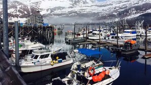A marina with boats docked, a building in the background, and snow-covered mountains. - Inn at Whittier (Whittier)