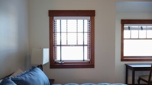 A bedroom with a bed, a window with blinds, a chair, and a desk. - Inn at Whittier (Whittier)