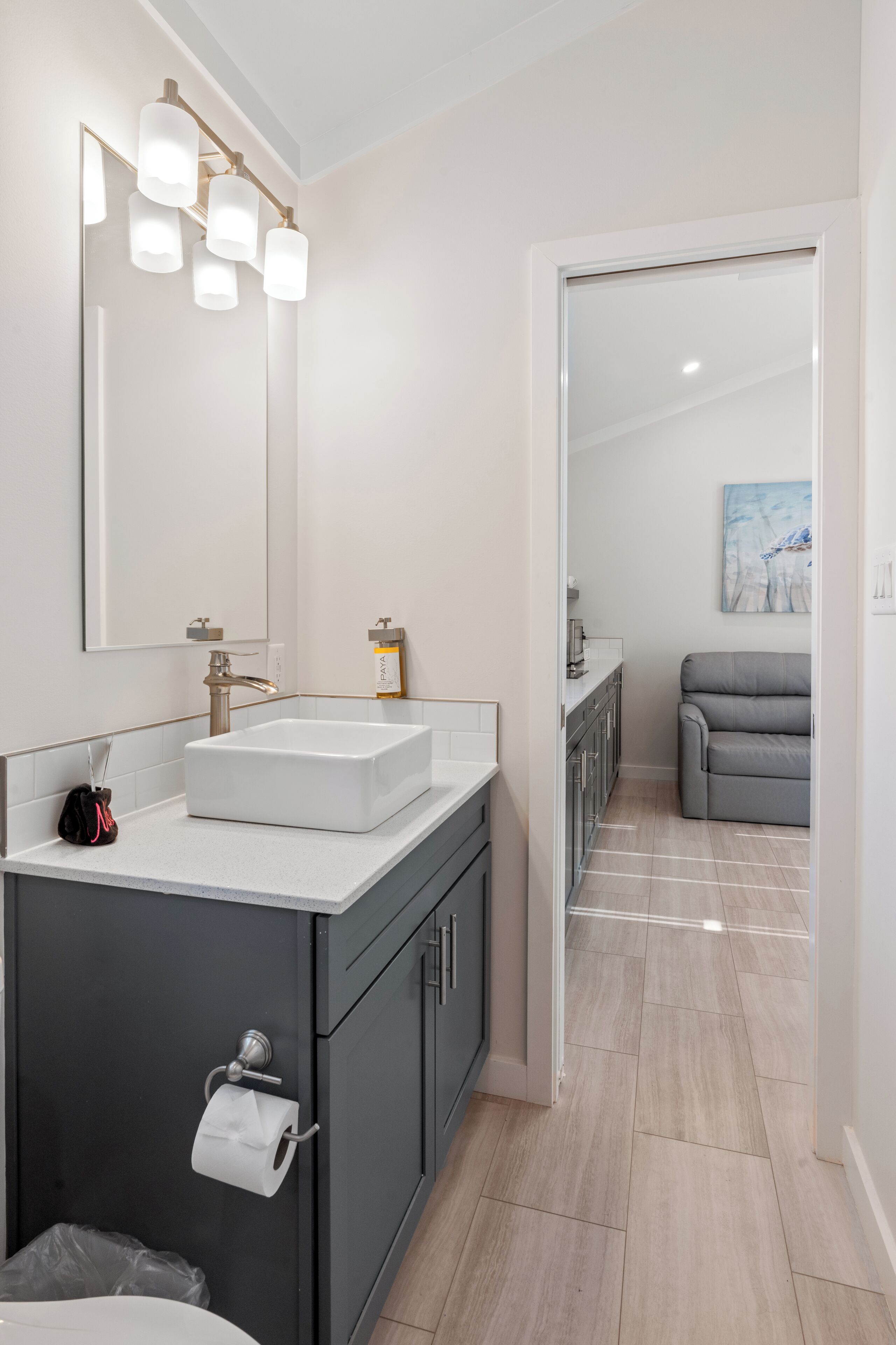 A modern bathroom with a white sink, a large mirror, and a light fixture.