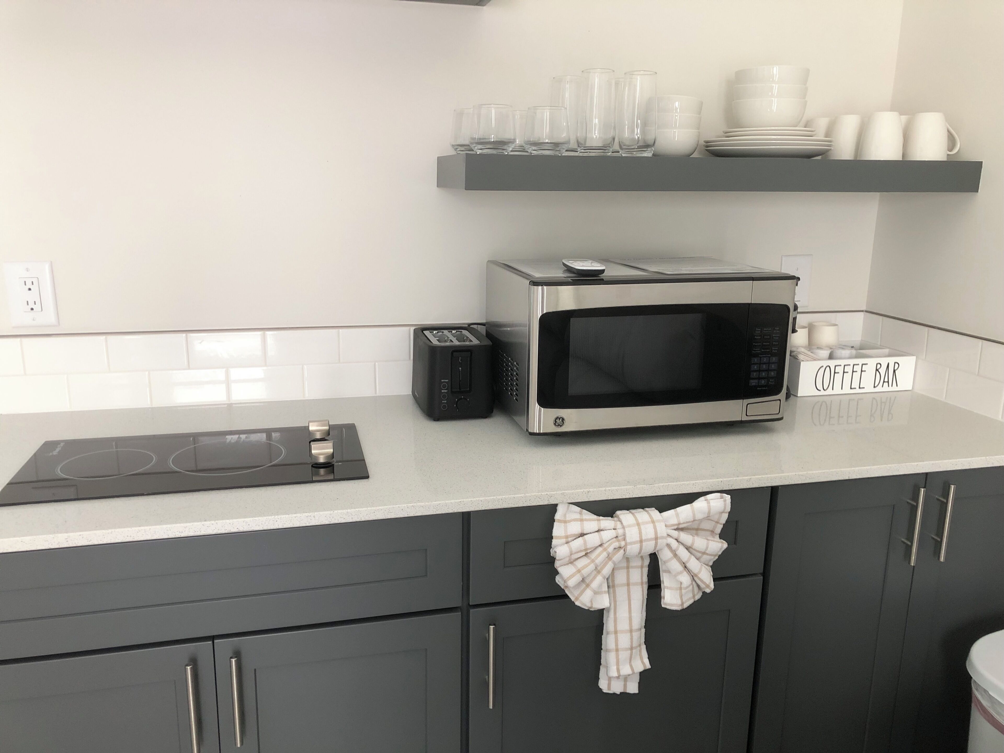 A kitchen with a microwave, toaster, and a coffee bar sign.