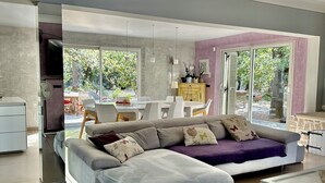 Een moderne woonkamer met een hoekbank, een eethoek en een keuken.