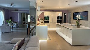 Een moderne keuken met witte kasten, een centraal eiland en een zithoek met een bank en salontafel.