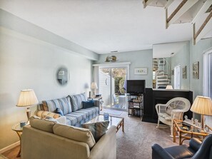 Ein Wohnzimmer mit einer Couch, einem Couchtisch, Sesseln, einem Fernseher und einem Bücherregal.