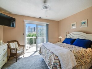Ein Schlafzimmer mit Bett, Stuhl, Schminktisch, Fernseher und einem Balkon mit Blick.
