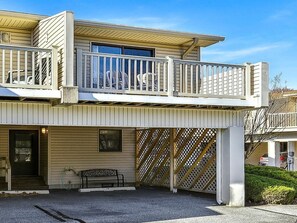 Ein zweistöckiges Gebäude mit Balkon, Eingangstür und einer Bank.