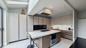 A modern kitchen with a central island, built-in appliances, and a skylight. - Bright Ensuite Room in Shared Wandsworth Flat (London)