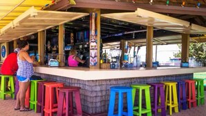 Uma área de bar com banquetas coloridas e um balcão.