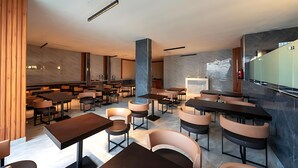 A modern hotel lobby with marble flooring, multiple seating areas, and a large wall-mounted screen. - Pearly Hotel (Abha)