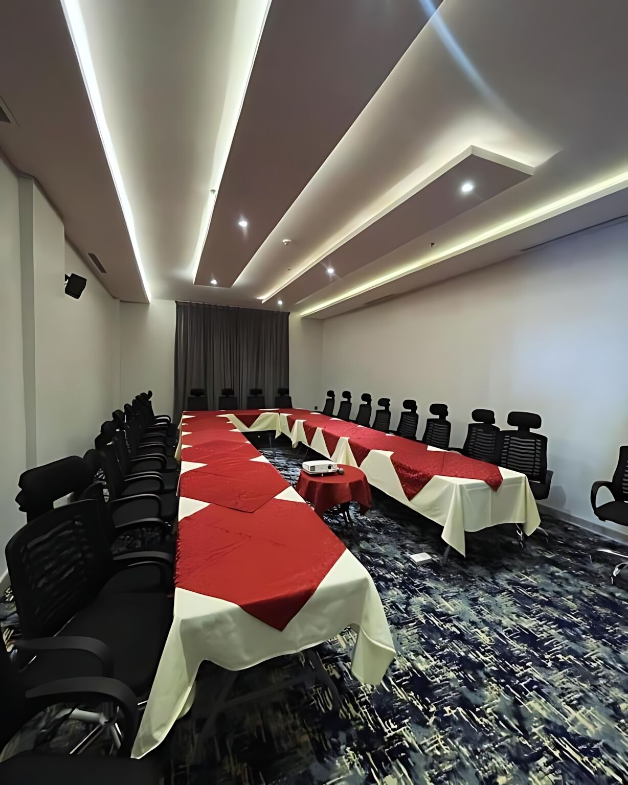Una sala conferenze con un lungo tavolo, sedie e pavimento con tappeto.