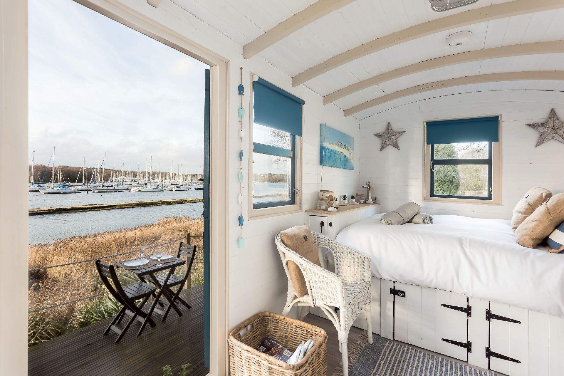 A bedroom with a bed, a desk, and a view of a marina.