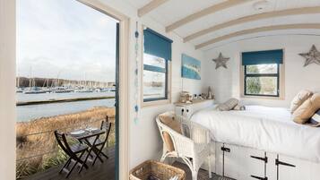 A bedroom with a bed, a desk, and a view of a marina.