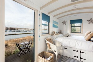 A bedroom with a bed, a desk, and a view of a marina.
