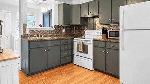 A modern kitchen with dark cabinets, a white stove, and a microwave. - Grace on the Lake-Little Red Cabin-Perch Lake, MI (South Boardman)
