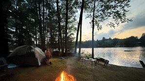 A campsite with a tent, a campfire, and a lakeside view. - Grace on the Lake-Little Red Cabin-Perch Lake, MI (South Boardman)