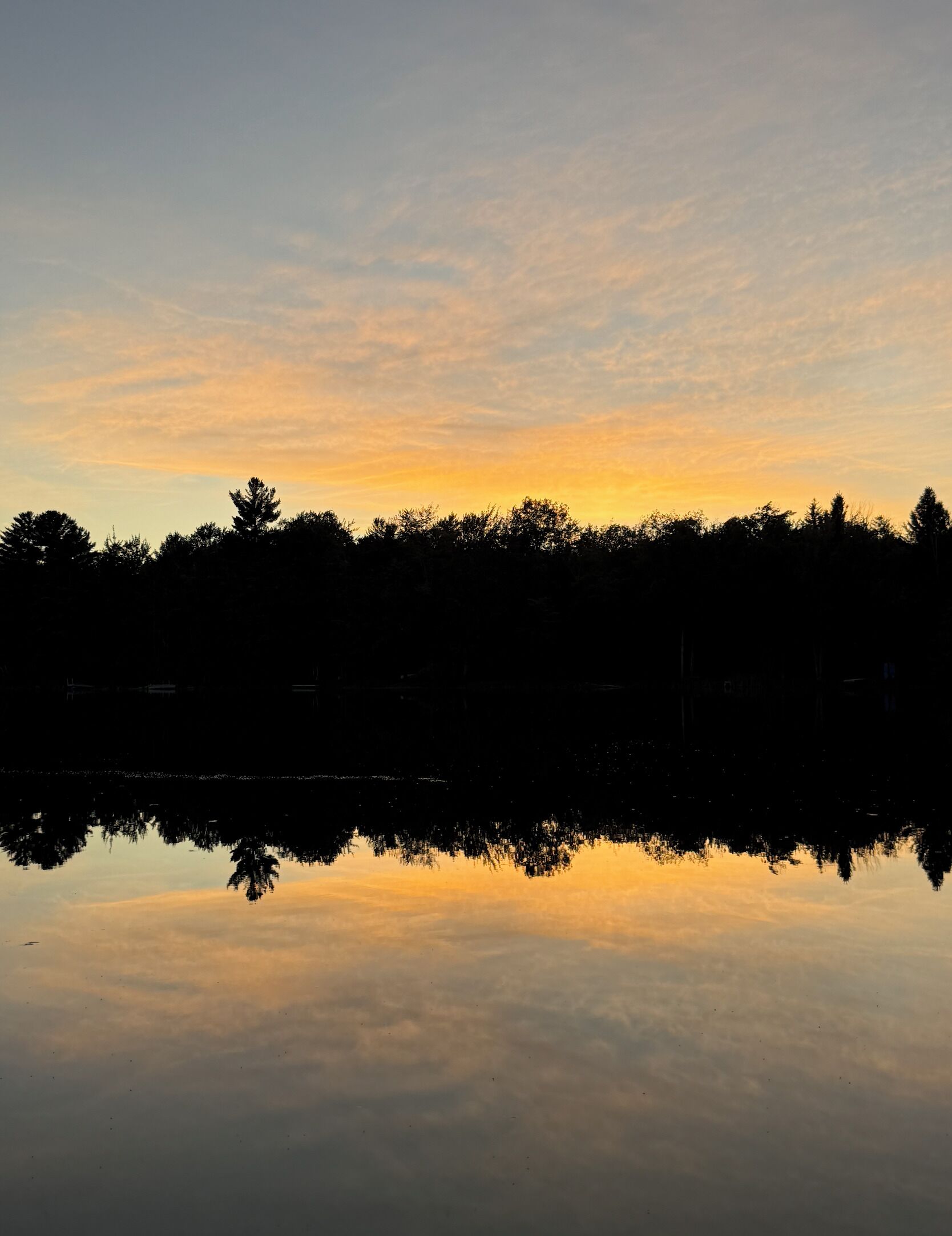 Een rustig meer dat de lucht weerspiegelt tijdens zonsondergang.