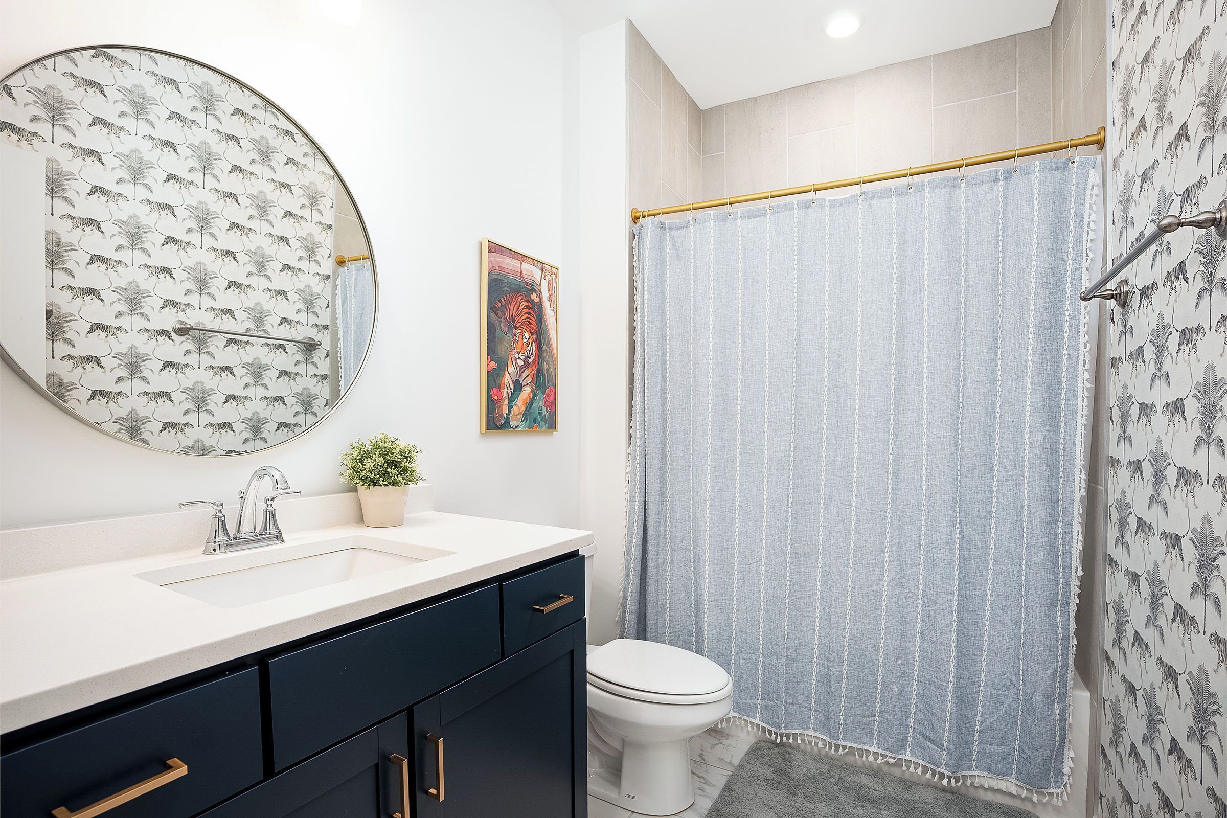 A bathroom with a round mirror, a sink, a toilet, and a shower curtain.