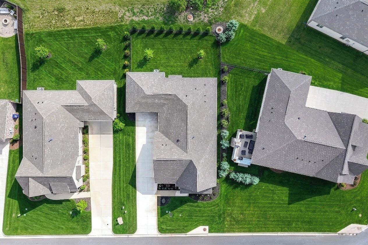 An aerial view of a residential area with multiple houses, each featuring a distinct architectural style with sloped roofs and varying window placements.