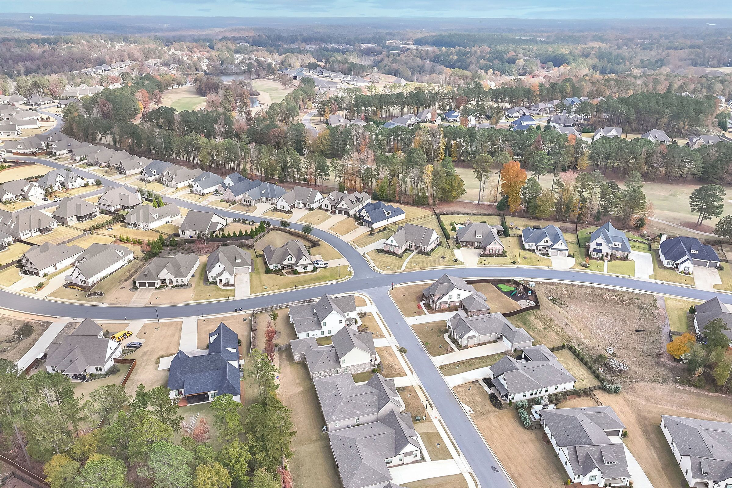An aerial view of a residential area with houses, roads, and a golf course.